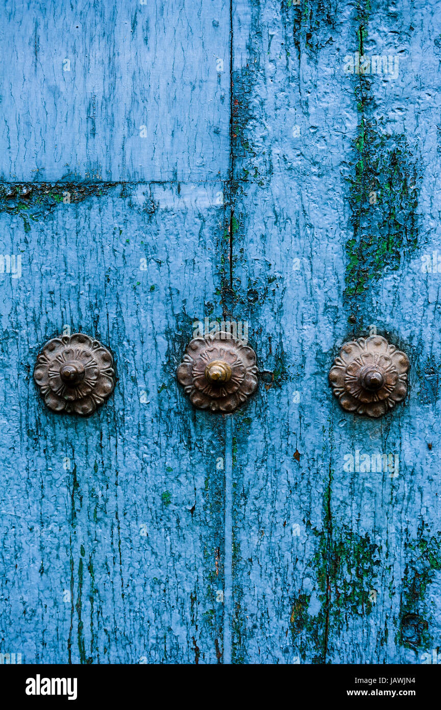 Espárragos de acero en una puerta de madera azul desgastada en la Cordillera de Los Andes. Foto de stock