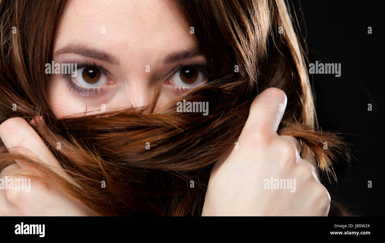 Close-up retrato de una bella mujer cubre el rostro por largos pelos marrones Foto de stock