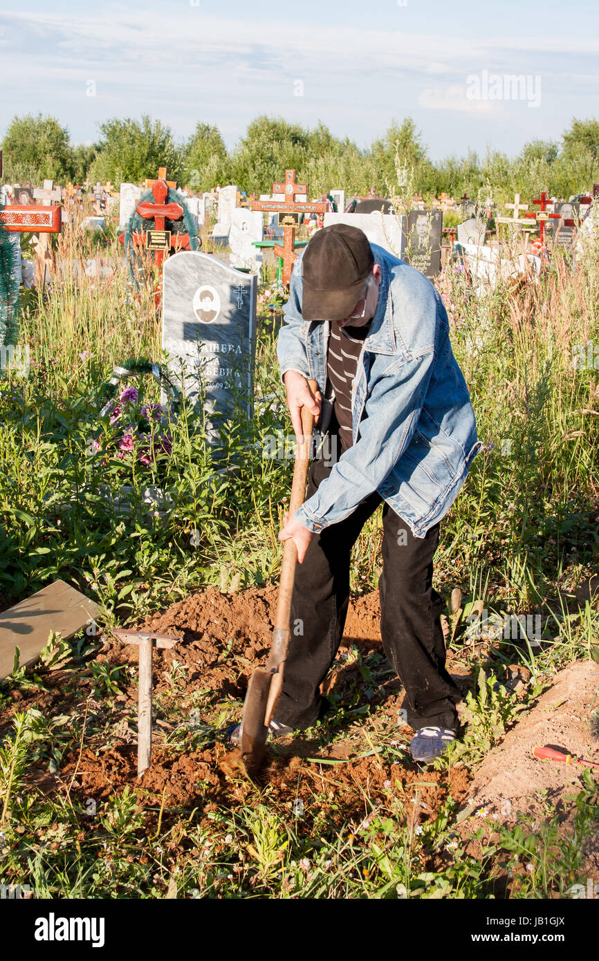 Perm, Rusia - julio 13.2016: el hombre establece un banco sobre una tumba en un cementerio Foto de stock