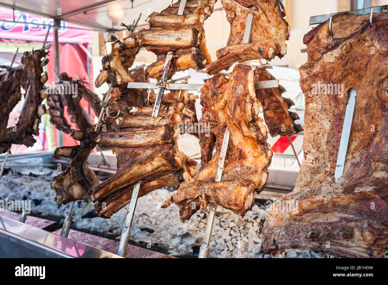 La carne asada de carne de vacuno cocinada en un parrillas verticales colocados alrededor del fuego. Asado, parrillada tradicional plato en Argentina Foto de stock