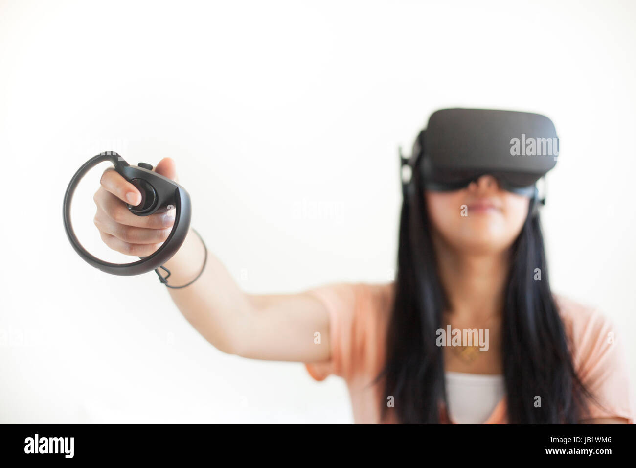 Joven mujer asiática vistiendo casco de realidad virtual oculus rift y demostrar cómo utilizar el control táctil Foto de stock