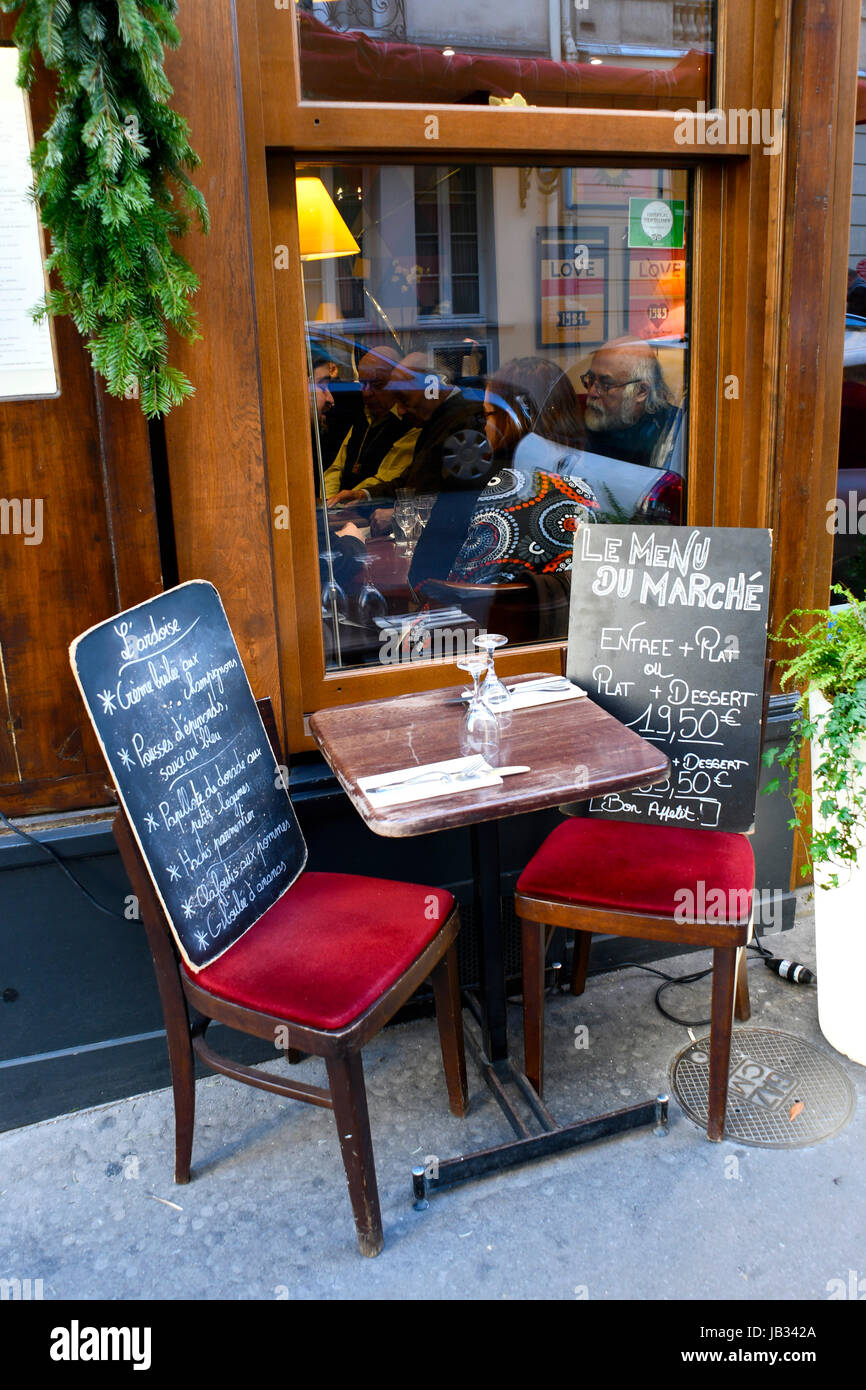Dos pizarras en dos sillas en una mesa bistro exterior presente el menú  diario de un pequeño restaurante en el distrito de Saint-Germain-des-Pres,  el 7º arrondissement de París, Francia Fotografía de stock -