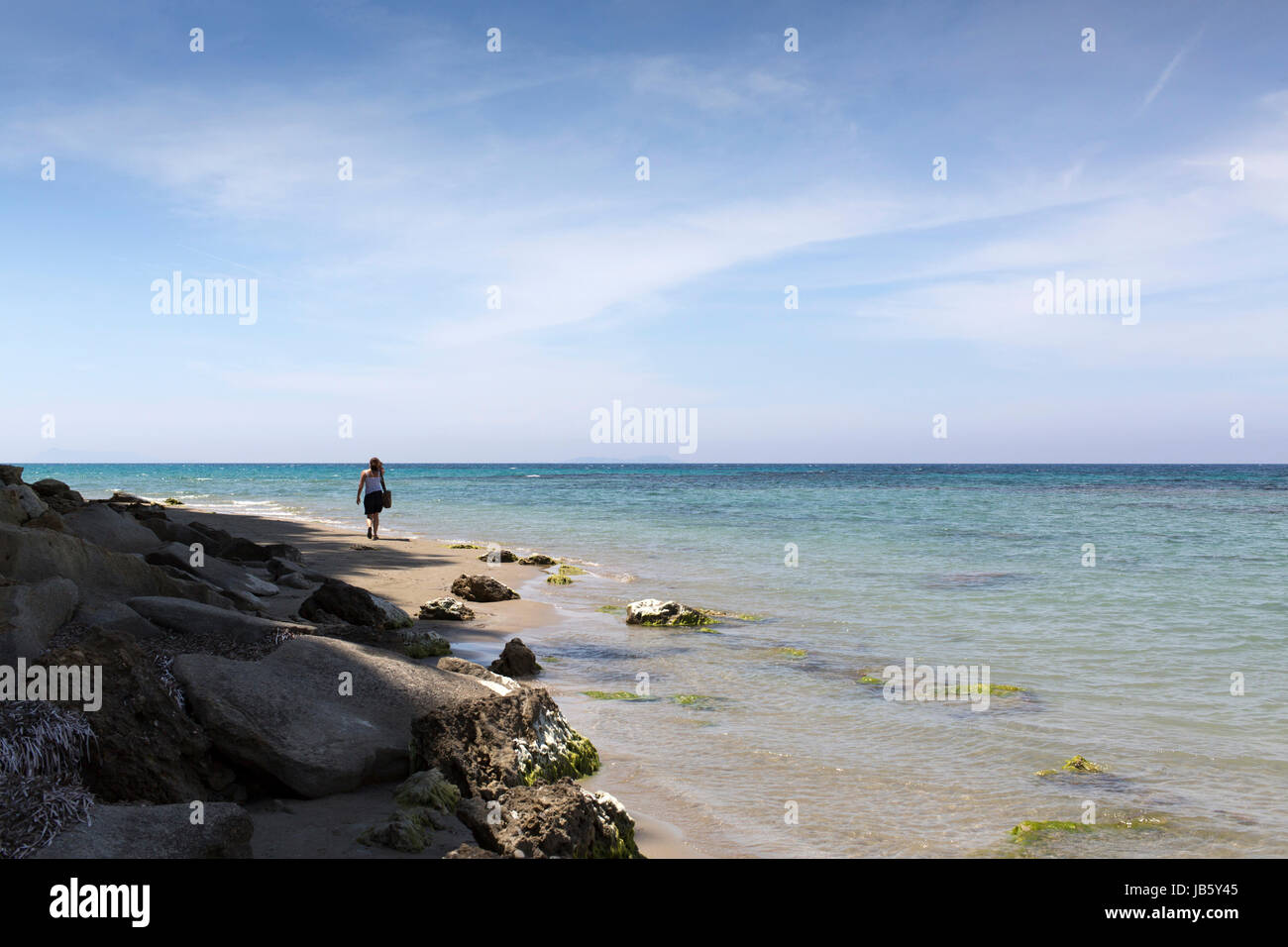 Mujer caminando por la playa en Corfu Foto de stock