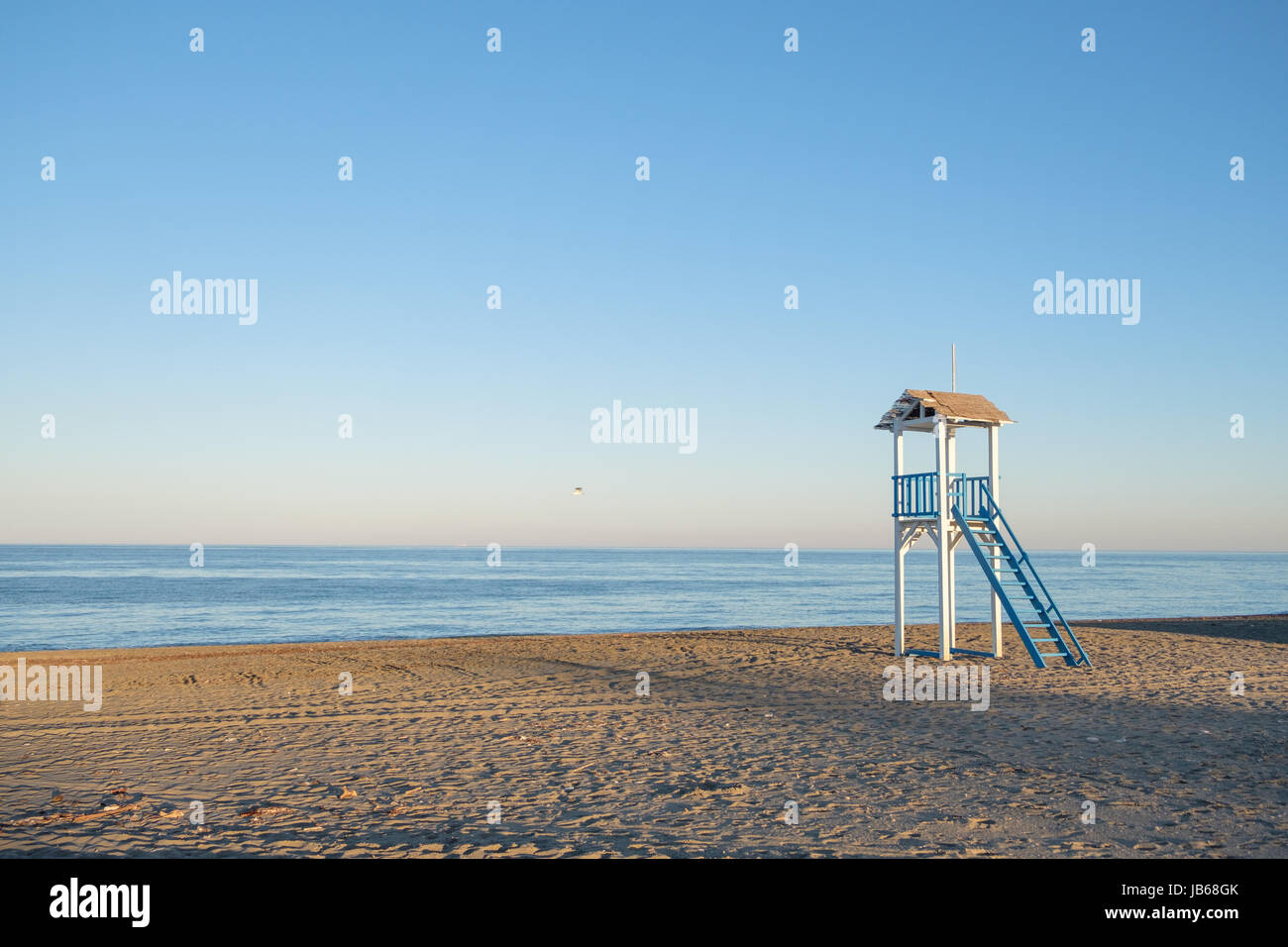 Azul y blanco cabaña protector de la vida en una playa al atardecer. Foto de stock
