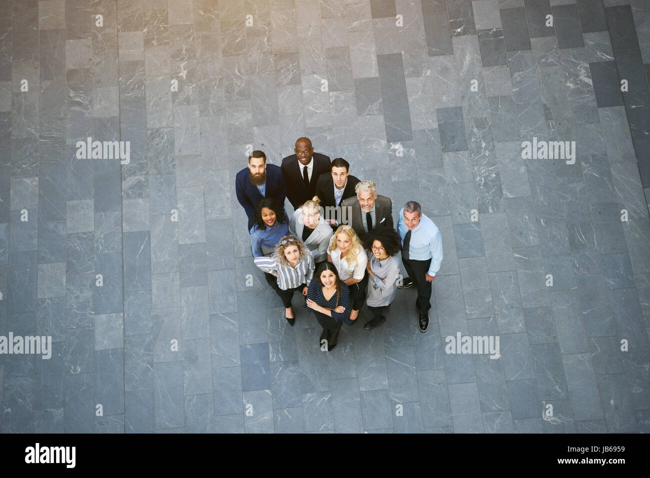 En blanco y negro por encima de los hombres y mujeres de negocios de pie en una sala grande y mirando juntos. Foto de stock