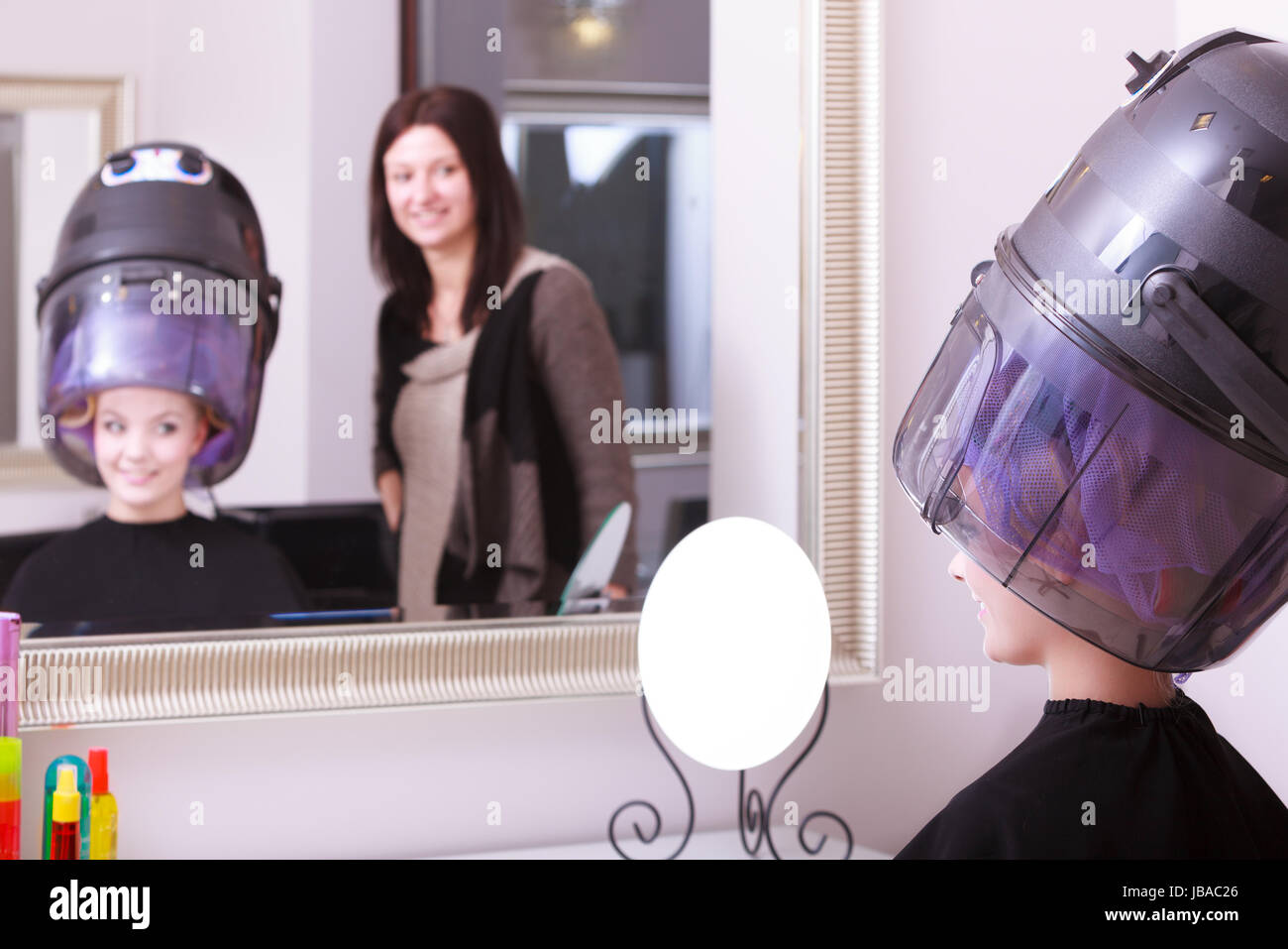 Mujer joven clienta en peluquería salón de belleza. Chica de rulos rulos  con secador de pelo relajante por el peluquero estilista Fotografía de  stock - Alamy