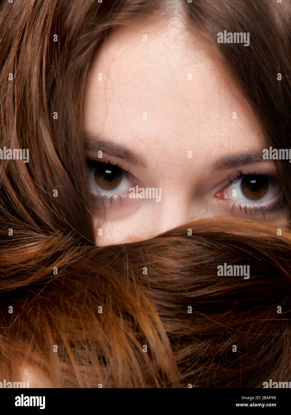 Close-up retrato de una bella mujer cubre el rostro por largos pelos marrones Foto de stock