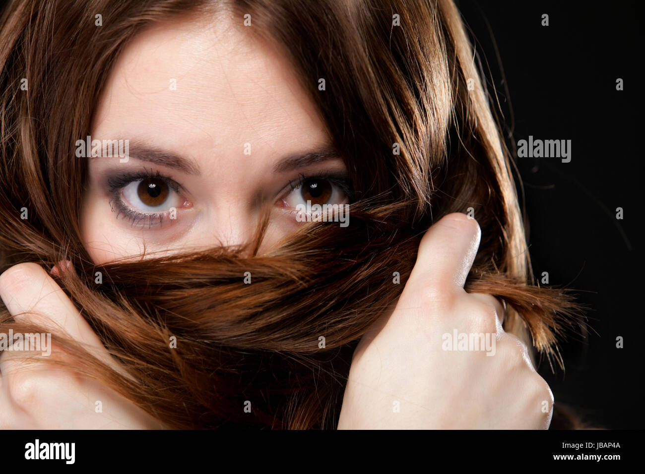 Close-up retrato de una bella mujer cubre el rostro por largos pelos marrones Foto de stock