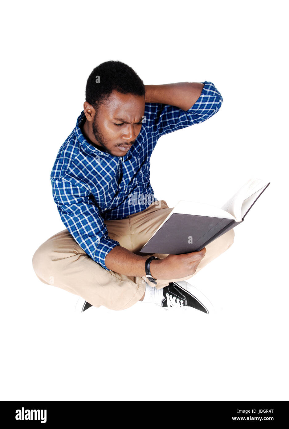 Un joven apuesto hombre afroamericano en beige pantalones y una camisa azul  sentada en el suelo, leyendo un libro, aislado sobre fondo blanco  Fotografía de stock - Alamy