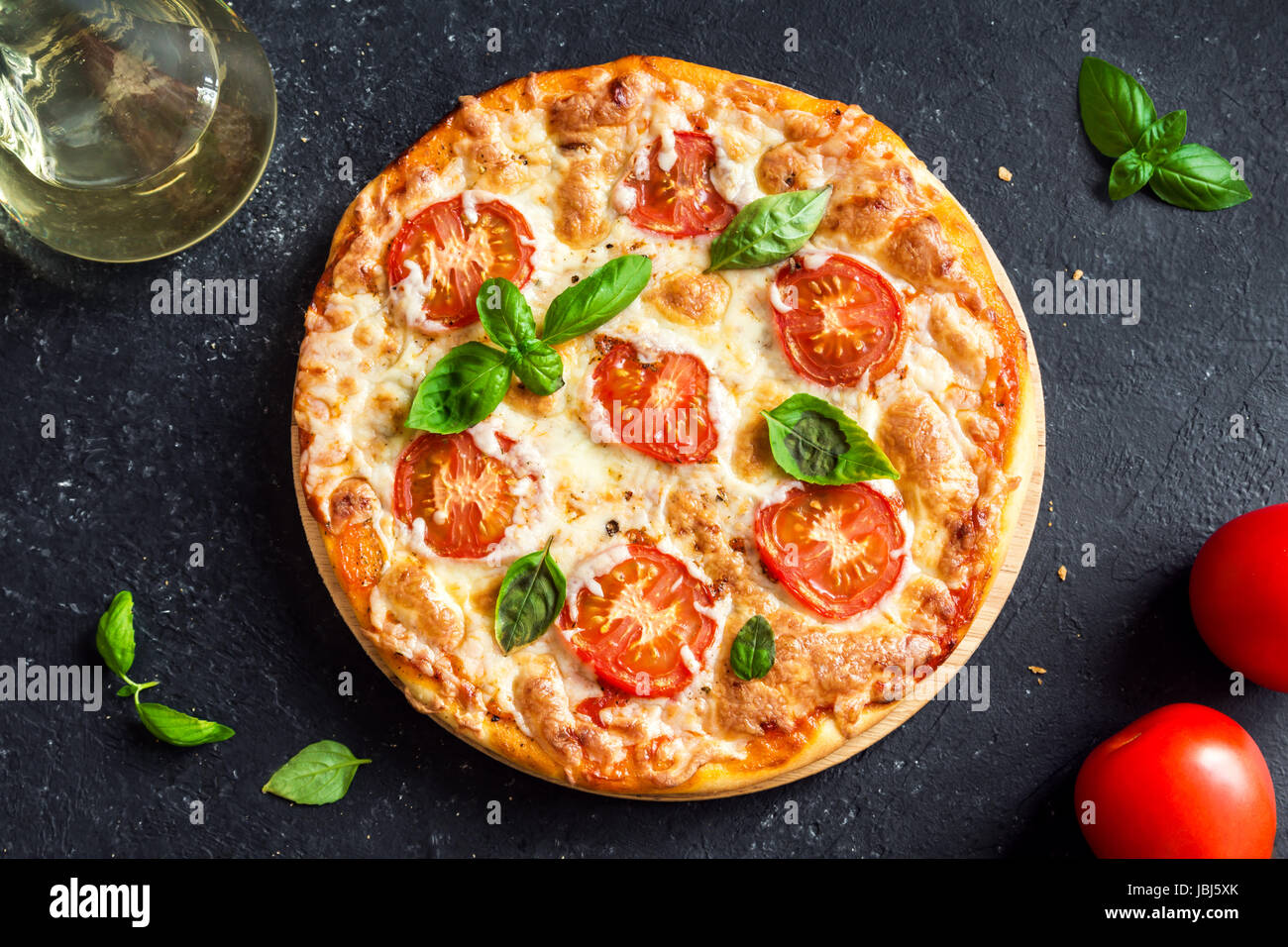 Pizza Margherita sobre fondo de piedra negra. Margarita Pizza casera con tomate, albahaca y queso mozzarella. Foto de stock