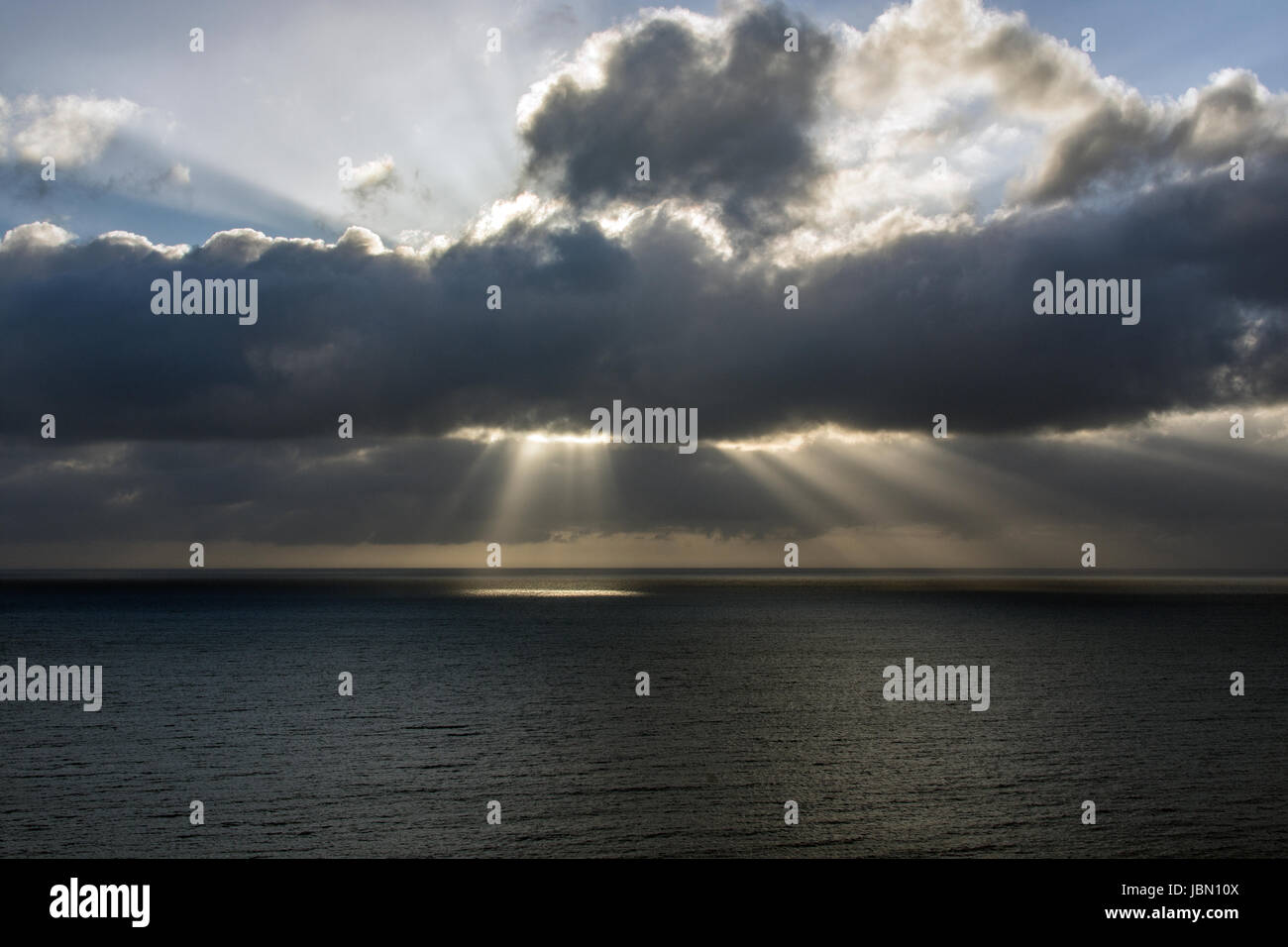 Una foto de Cardigan Bay frente a la costa de Aberystwyth. Los suns radios próximas a través de las nubes y la iluminación hasta el mar. Foto de stock