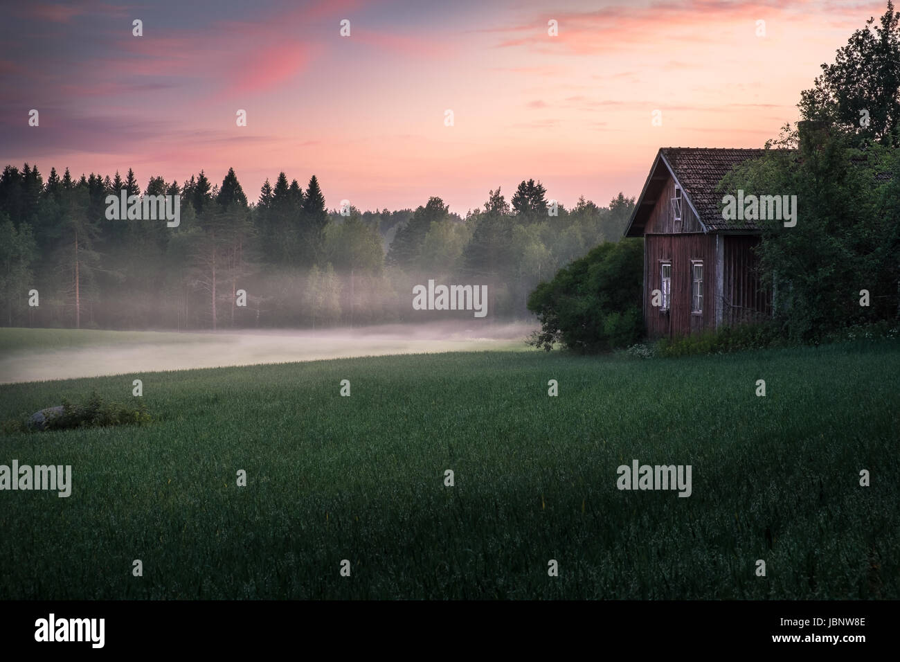 Pintoresco paisaje con campo y antigua casa de campo en noche de verano en Finlandia Foto de stock
