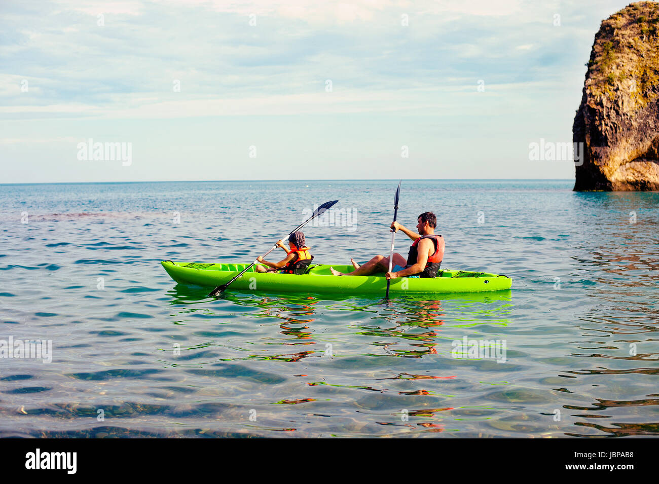 Hombre y niño nade en kayak en el mar de fondo de la isla. Kayak