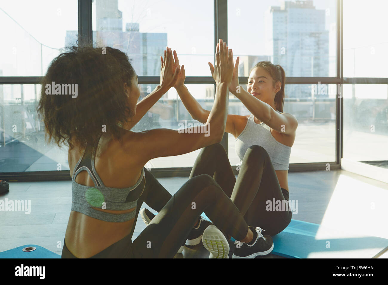 Dos jóvenes mujeres haciendo ejercicio en el gimnasio, haciendo ejercicios abdominales Foto de stock