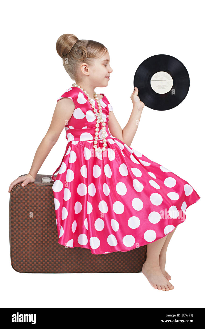 Vestida con un estilo retro chica sentada en la vieja maleta Foto de stock