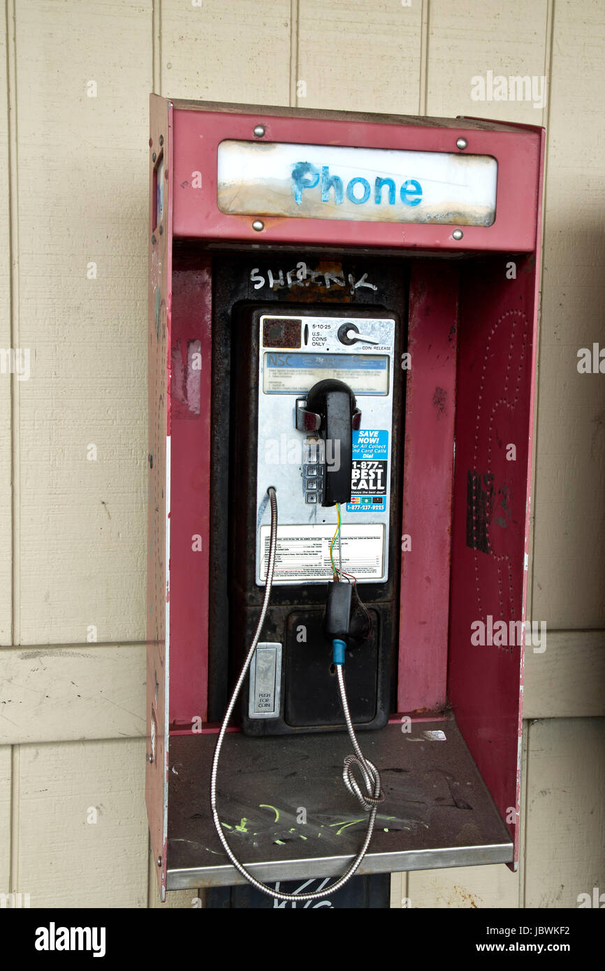 Abandonada teléfono público de monedas con ranura de liberación de moneda, graffiti. Foto de stock