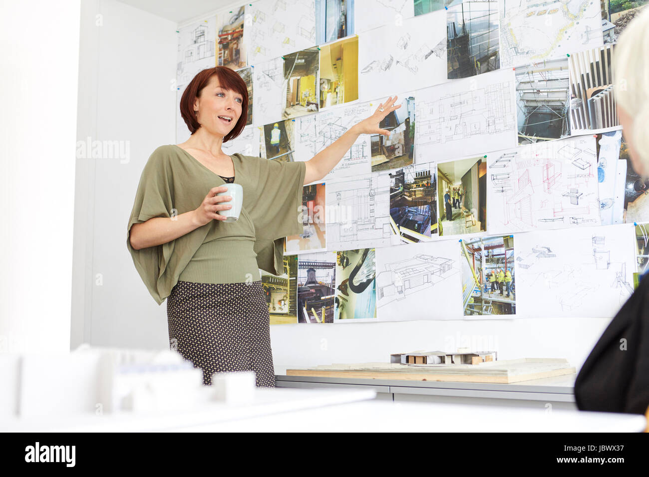 Arquitecto femenino apuntando a bordo de humor en la presentación de oficina Foto de stock