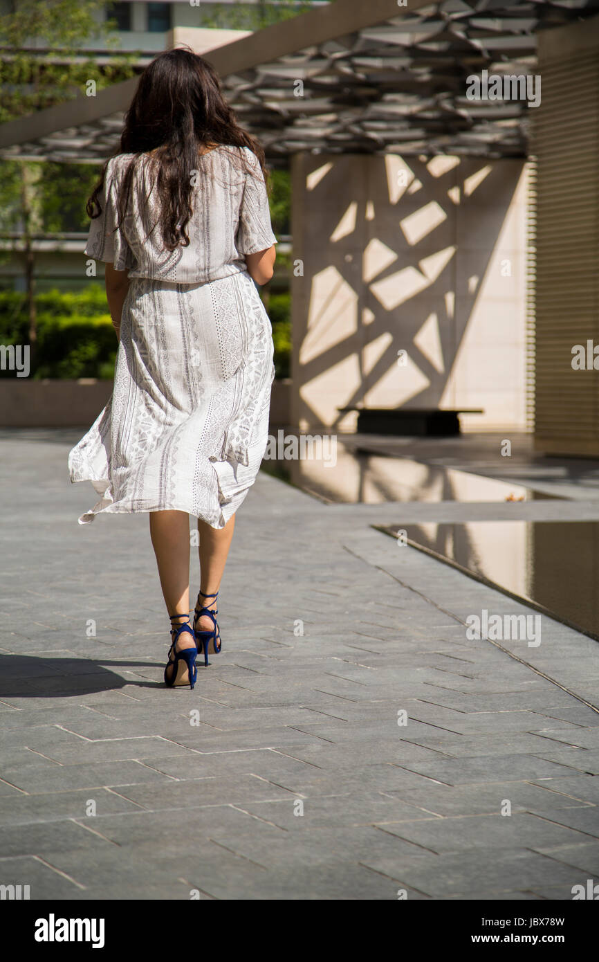 Vista trasera de una mujer que llevaba un vestido caminando en la ciudad Foto de stock