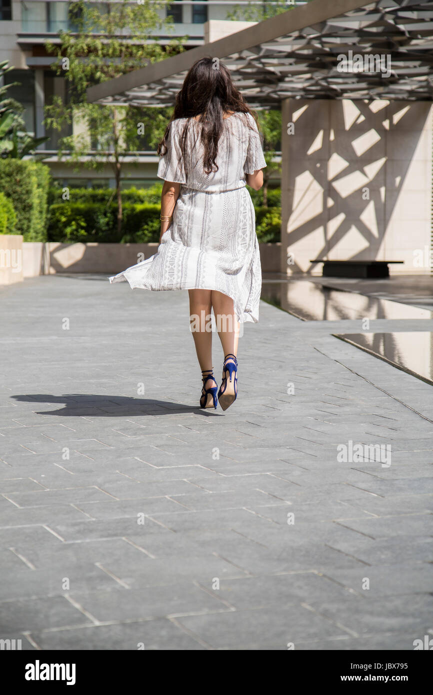 Vista trasera de una mujer que llevaba un vestido caminando en la ciudad Foto de stock