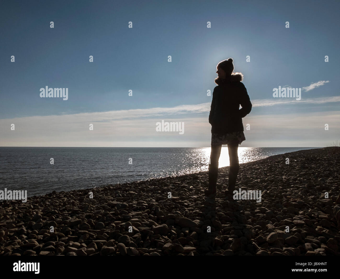 Una señorita siluetas contra la puesta de sol en la costa de Gales del Sur Foto de stock