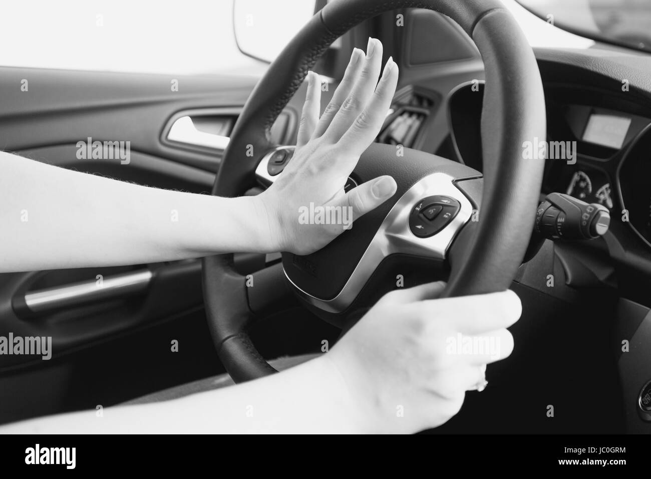 Persona que empuja el claxon mientras conduce sentado de un coche de prensa  de volante, sonido de bocina para advertir a otras personas en concepto de  tráfico.