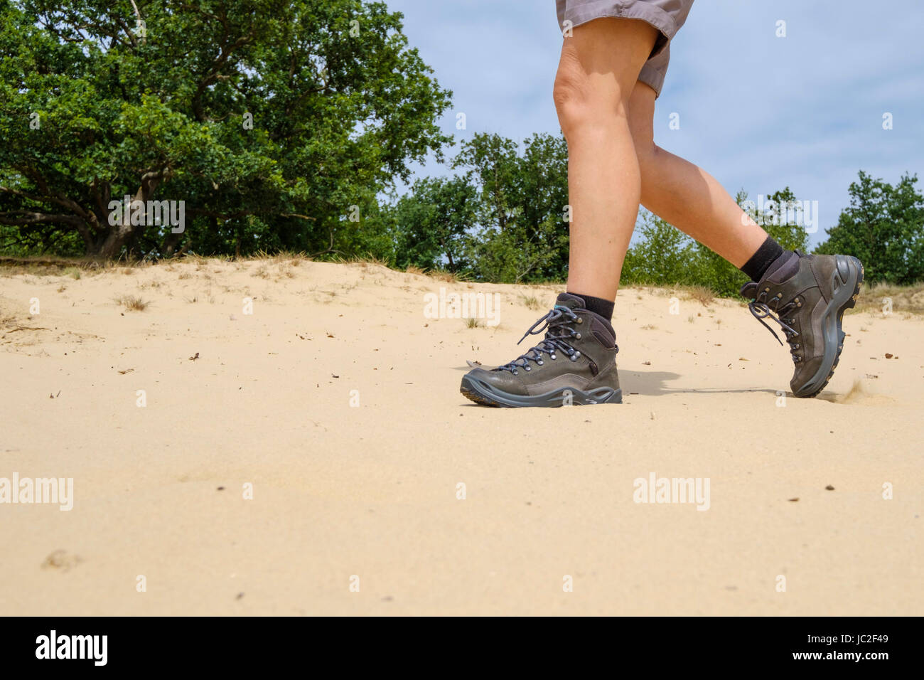 Mujer en pantalones cortos y botas de cuero caminando por la arena suelta  Fotografía de stock - Alamy