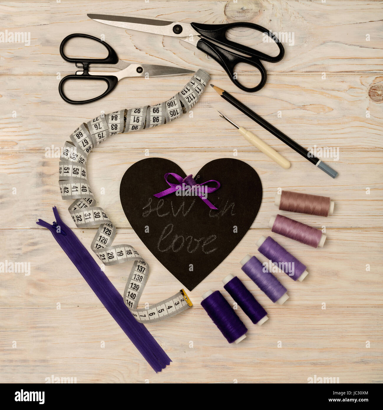 Accesorios de costura de color púrpura y el corazón con una inscripción - coser en el amor. El enfoque selectivo. Foto de stock