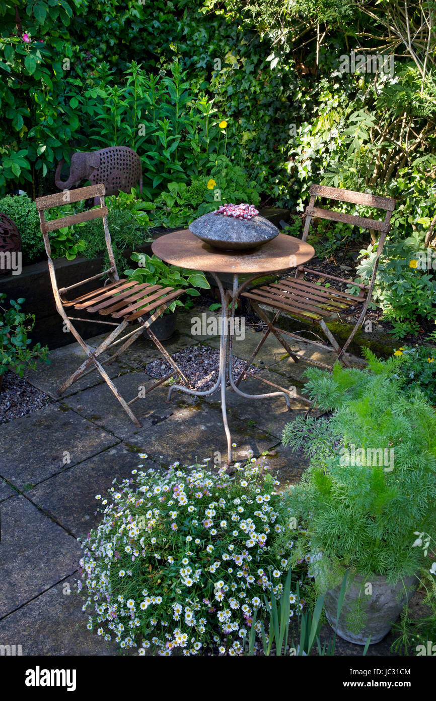 Mesa y sillas de metal en un bonito jardín inglés Foto de stock