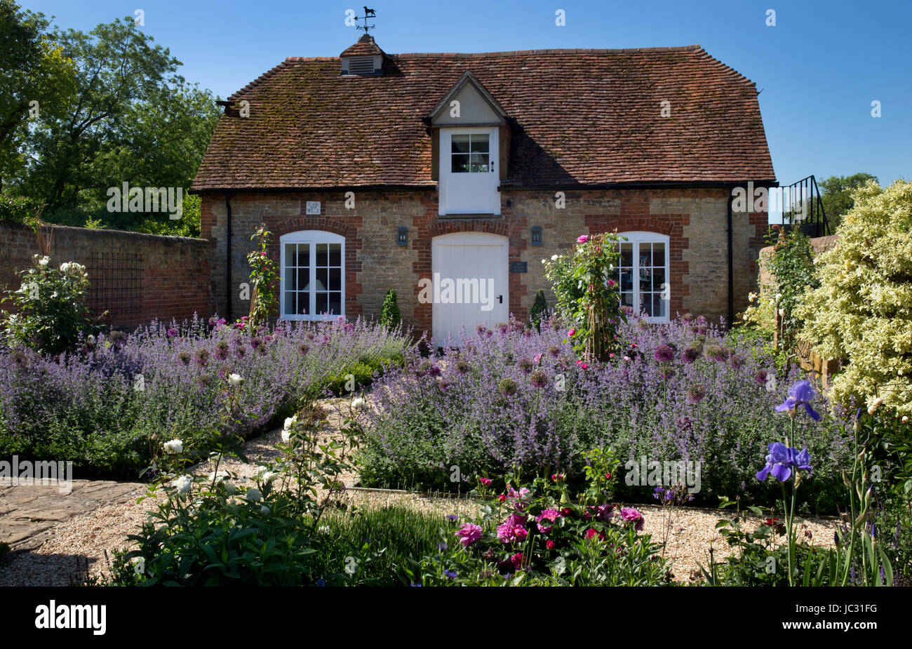 El camino de gravilla con fronteras de flores de verano en el jardín inglés Foto de stock