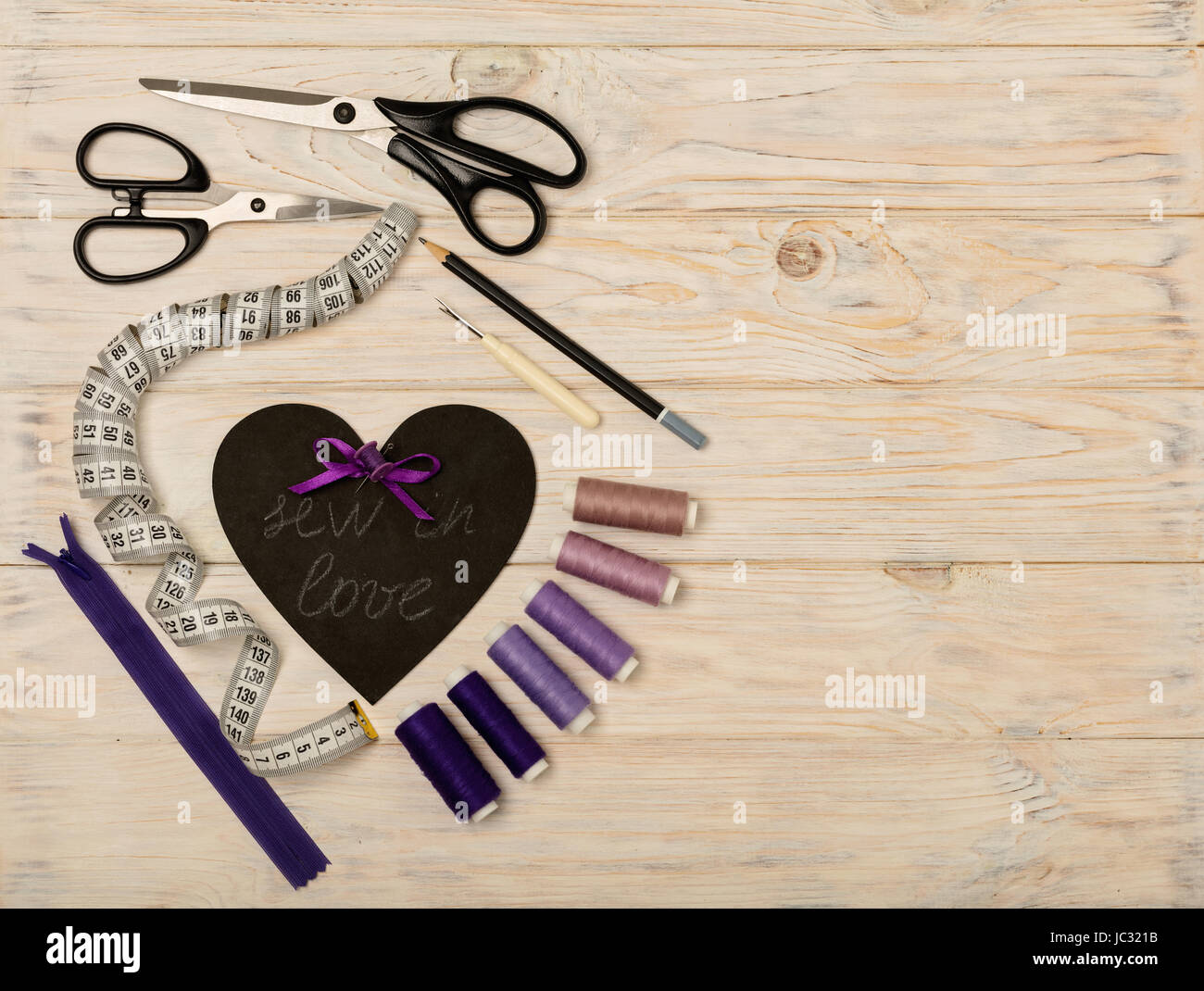 Accesorios de costura de color púrpura y el corazón con una inscripción - coser en el amor. El enfoque selectivo. Foto de stock