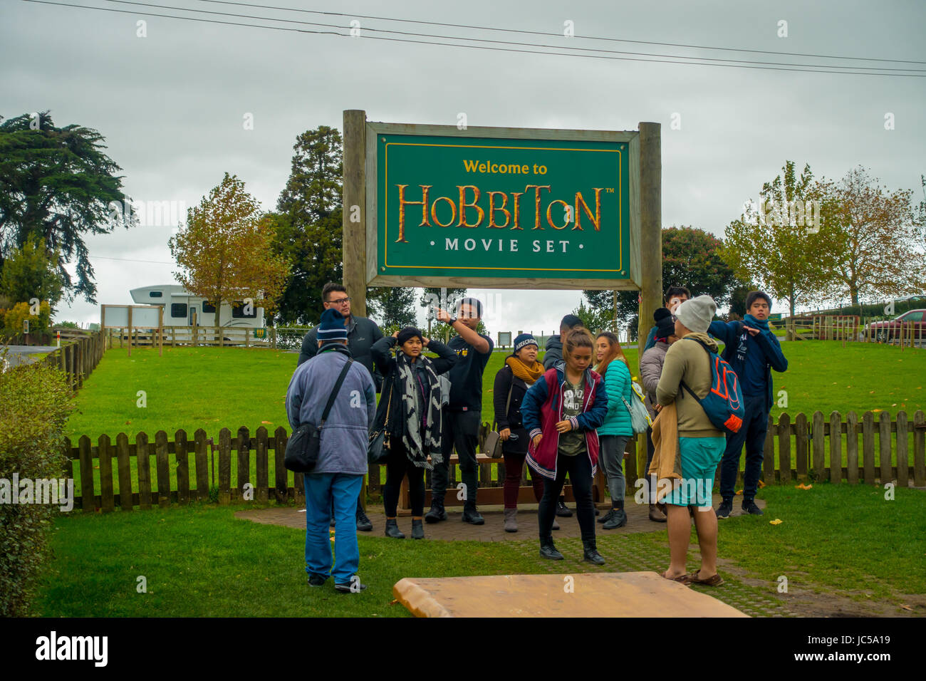 Isla del Norte, Nueva Zelanda- Mayo 16, 2017: Un pueblo no identificado posando en un cartel de bienvenida por la entrada a la aldea Hobbiton Hobbiton en películas. Foto de stock