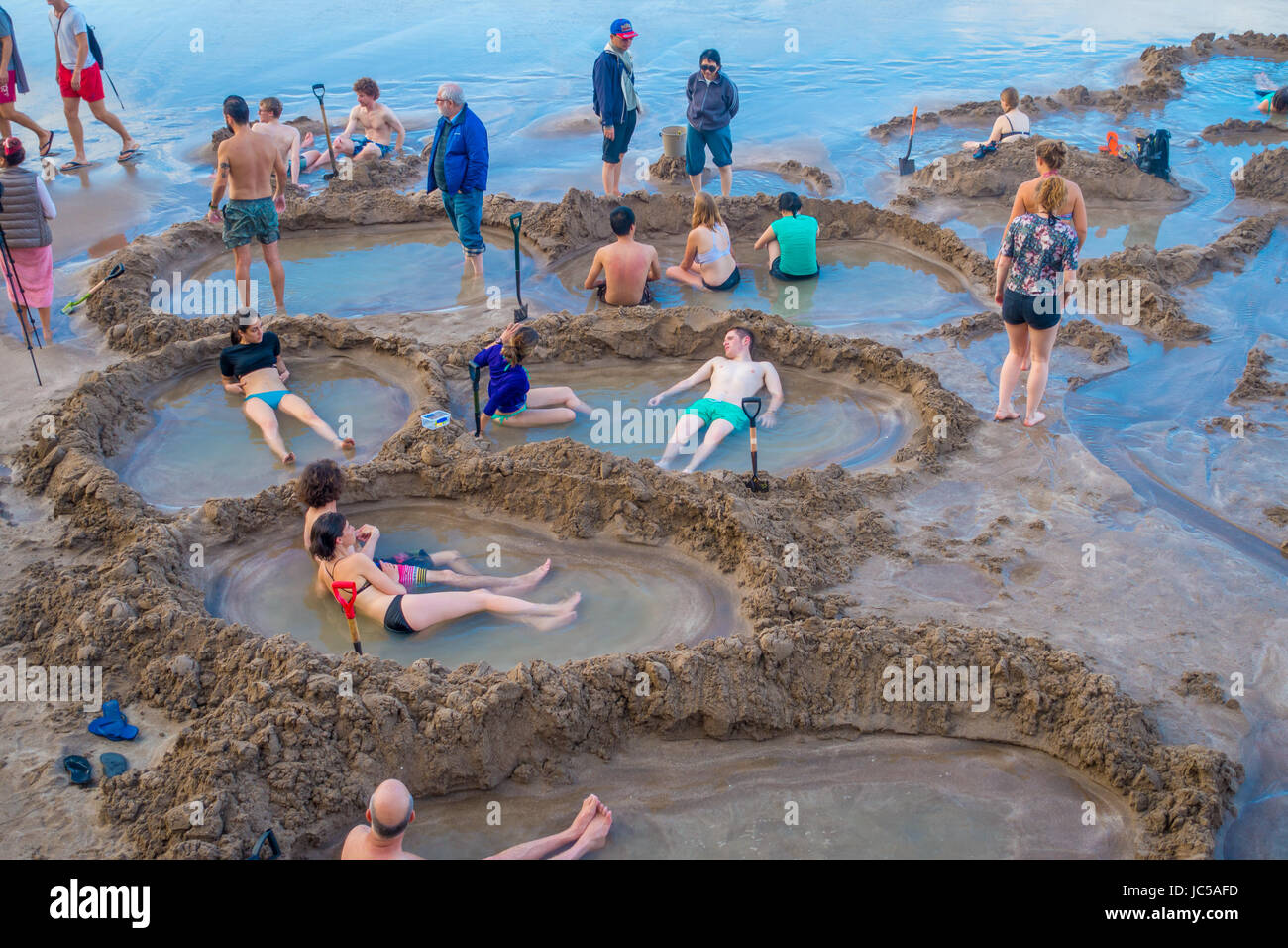 Isla del Norte, Nueva Zelanda- Mayo 16, 2017: los visitantes realizar pequeñas piscinas de agua caliente en la playa de agua caliente.es uno de los más populares atracciones geotermales en Foto de stock
