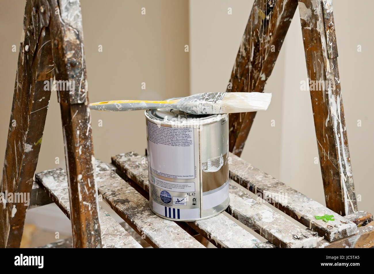 Cierre el pincel de pintura y la lata de pintura en las escaleras de mano Foto de stock