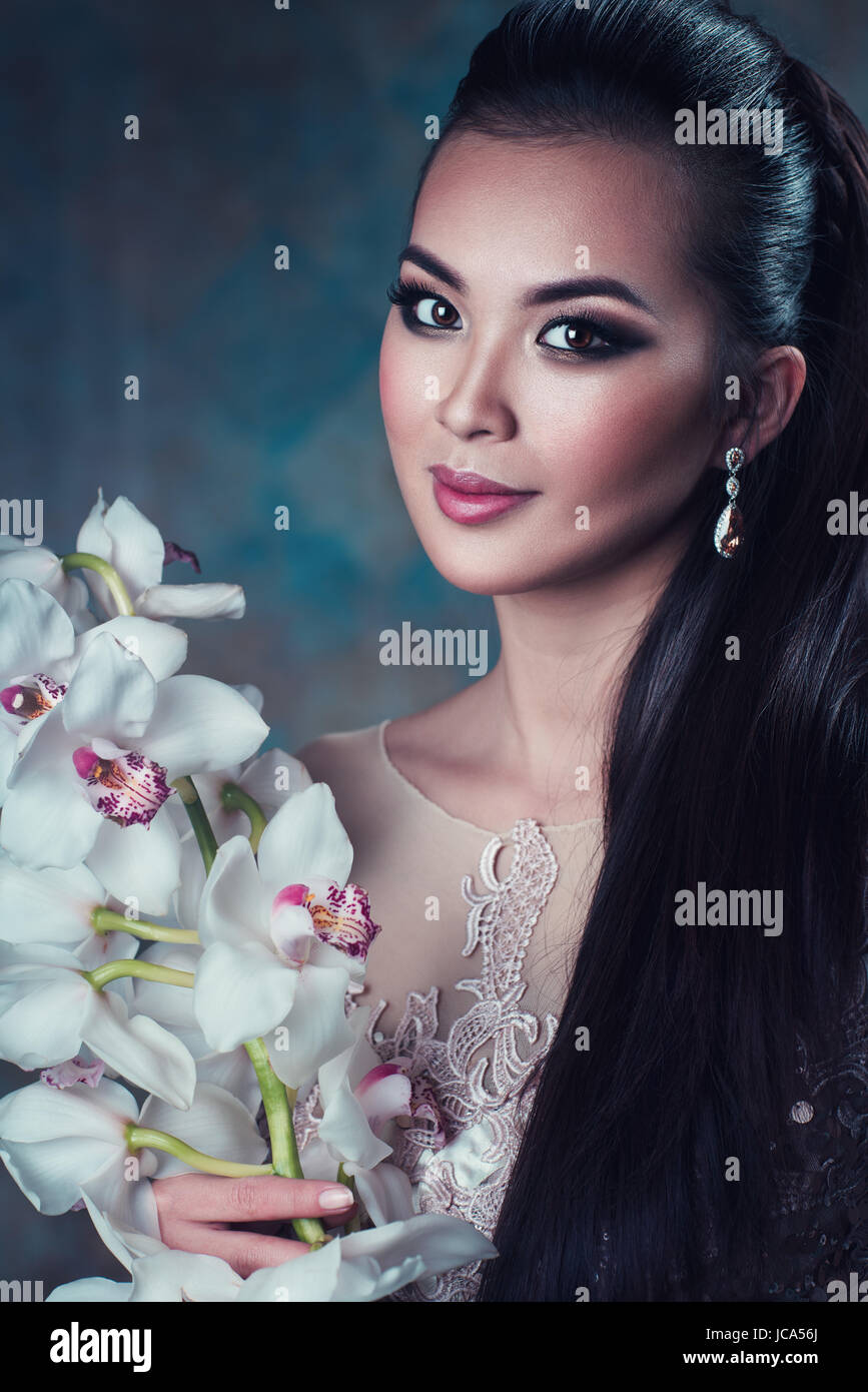 Joven mujer asiática con flor de orquídea retrato Foto de stock