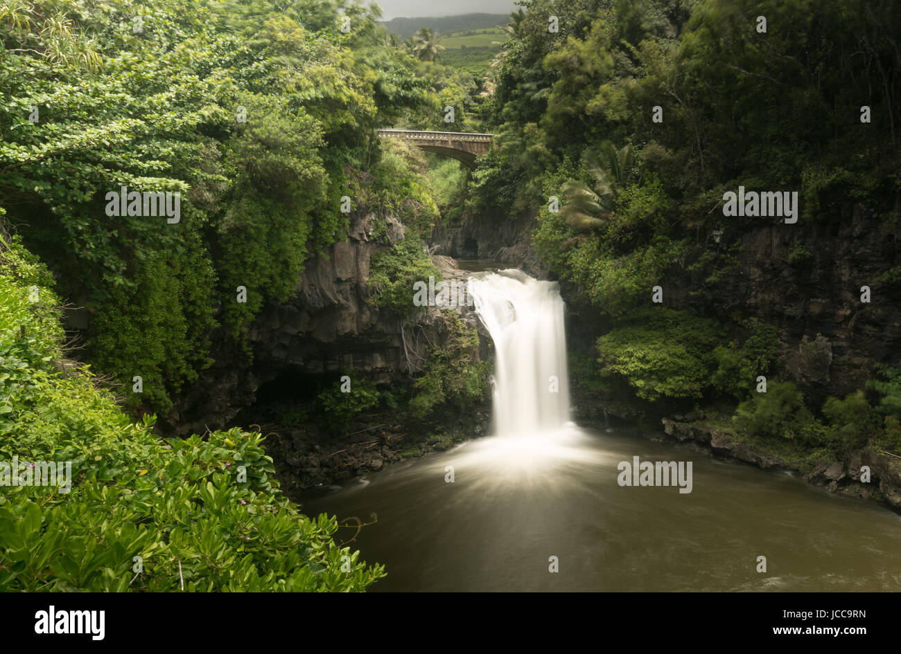 Cascada bajo el puente de carretera en siete piscinas sagradas Maui Foto de stock