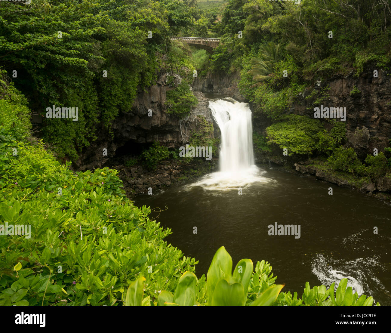 Cascada bajo el puente de carretera en siete piscinas sagradas Maui Foto de stock
