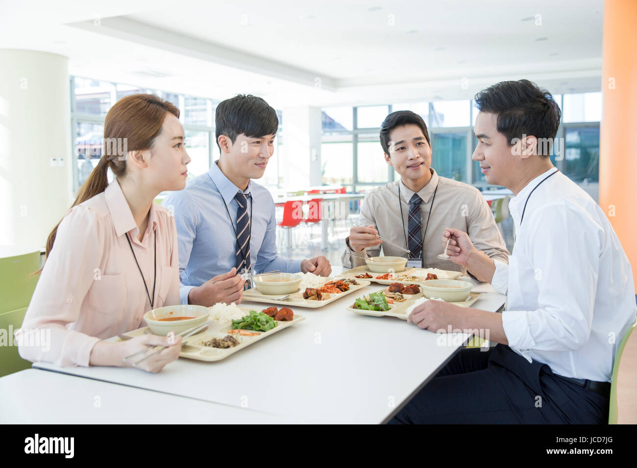 Compañeros sonriente tras hablar durante las comidas en la cafetería Foto de stock