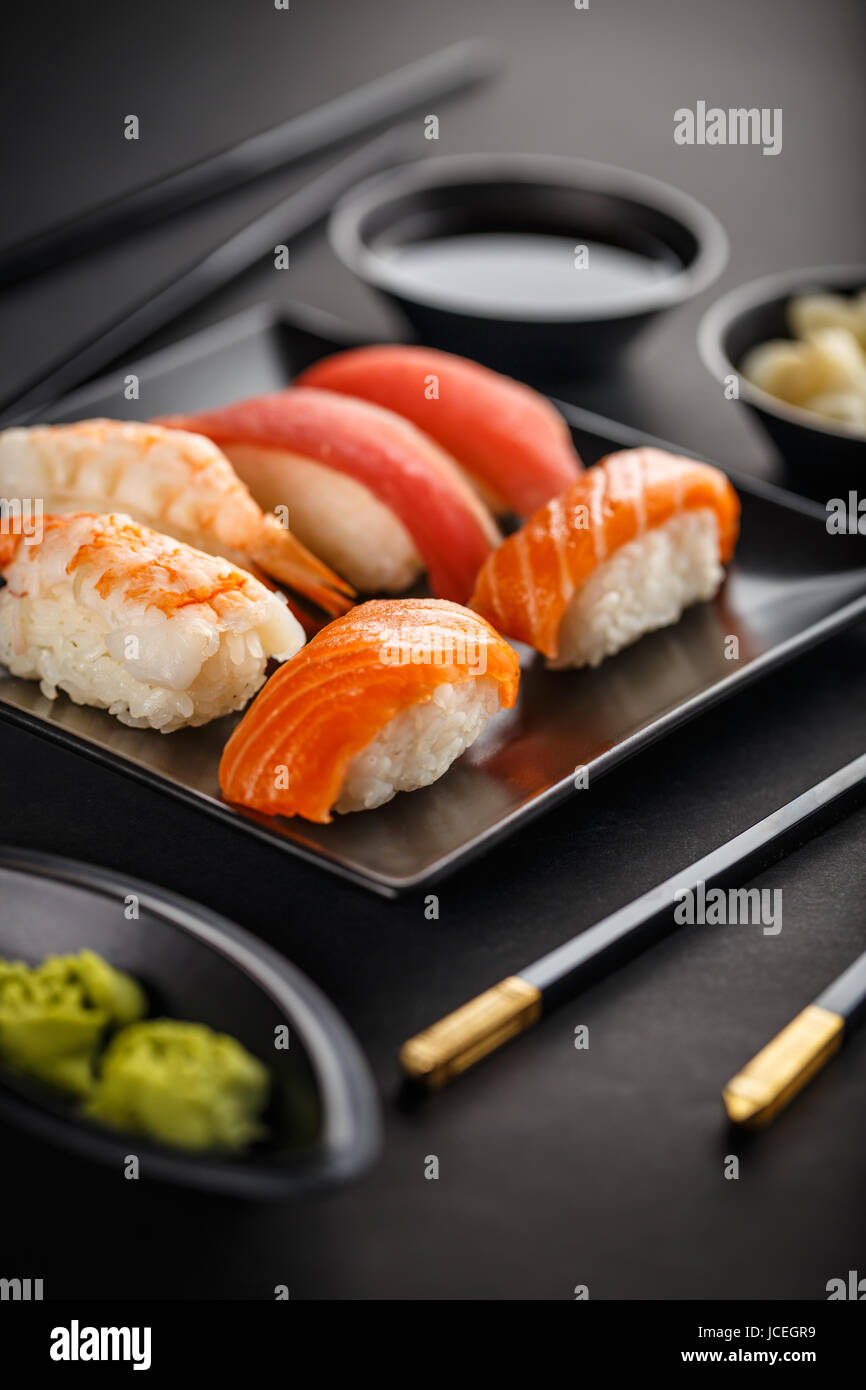 Plato de sushi con palillos sobre fondo negro Foto de stock