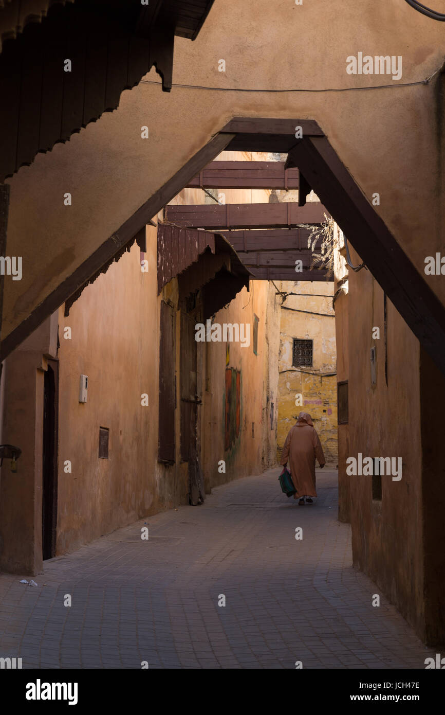 Un hombre camina a través de un callejón cubierto de Meknes, Marruecos Foto de stock