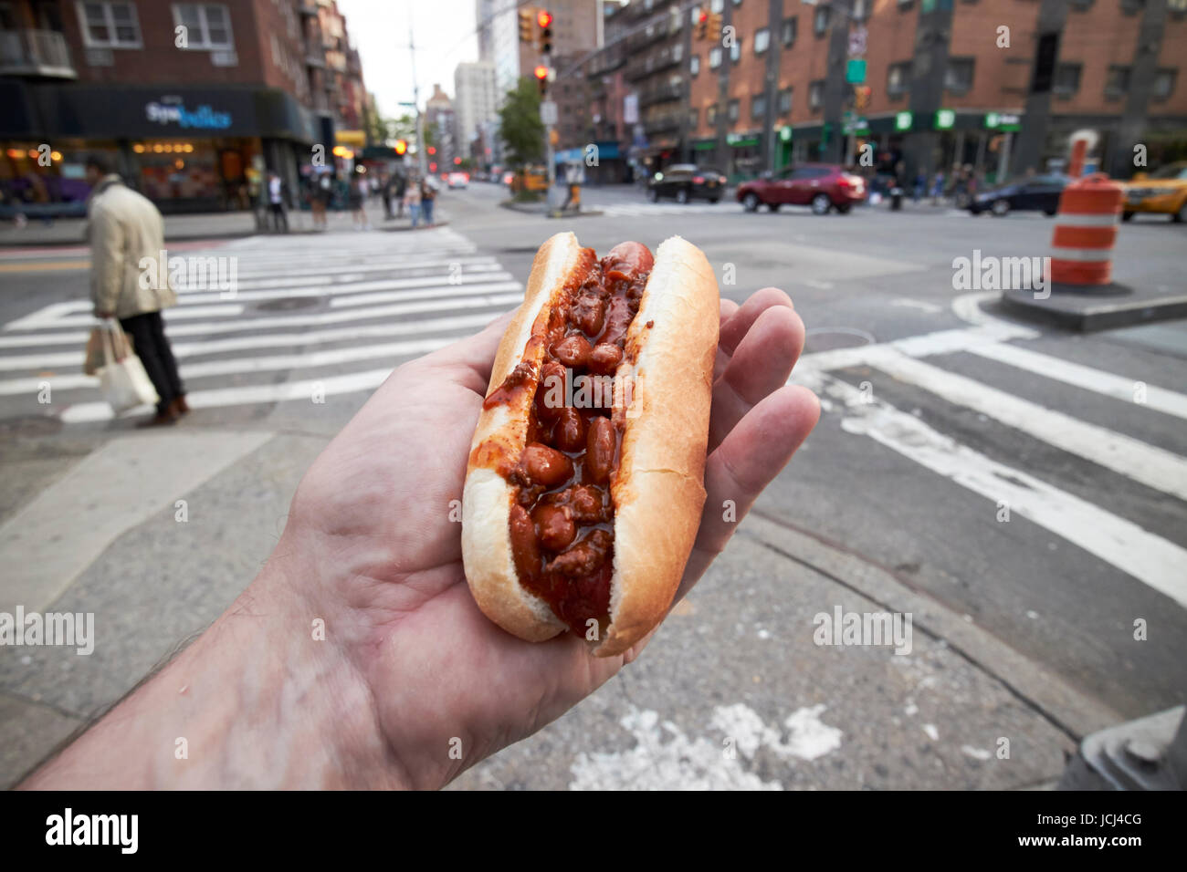 Hombre sujetando chili hot dog comida en la calle en la Ciudad de Nueva York, EE.UU. Foto de stock