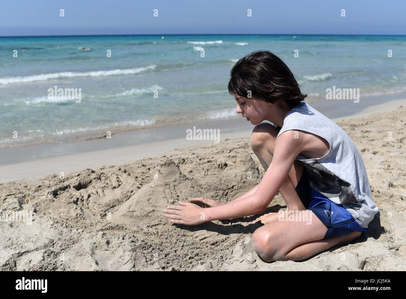 Chico de escultura en arena en una playa de arena fina, Menorca, España Foto de stock