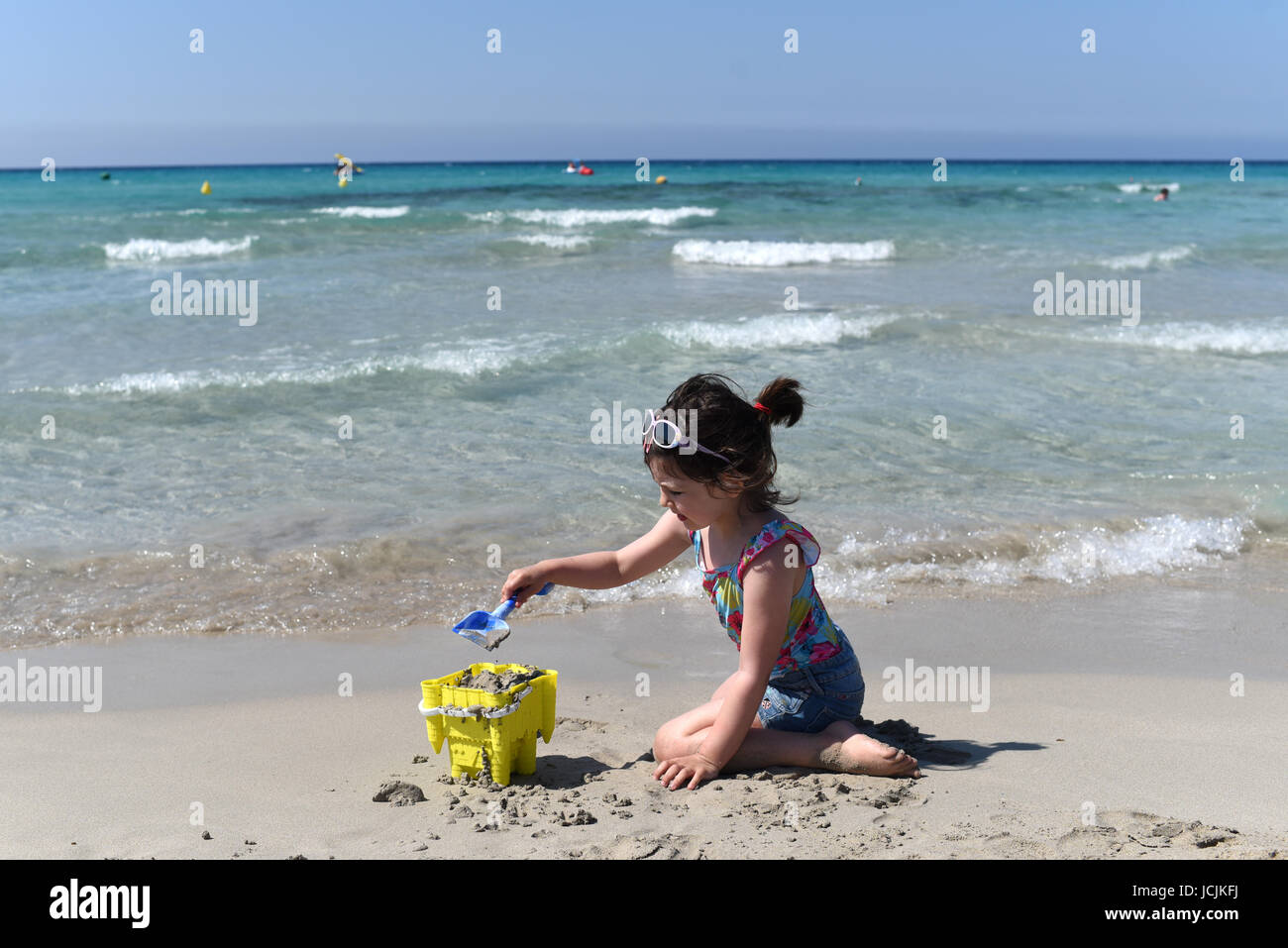 Niña pagando en una playa arenosa, Menorca, España Foto de stock