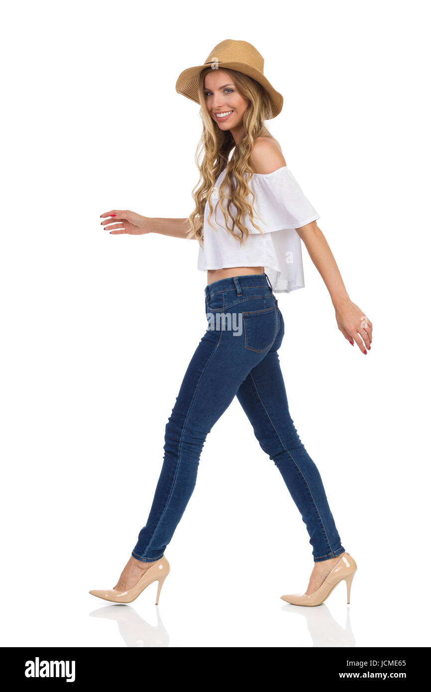 Mujer sonriente en jeans, camisa blanca y sombrero de paja Mujer sonriente en jeans, camisa blanca y sombrero de paja