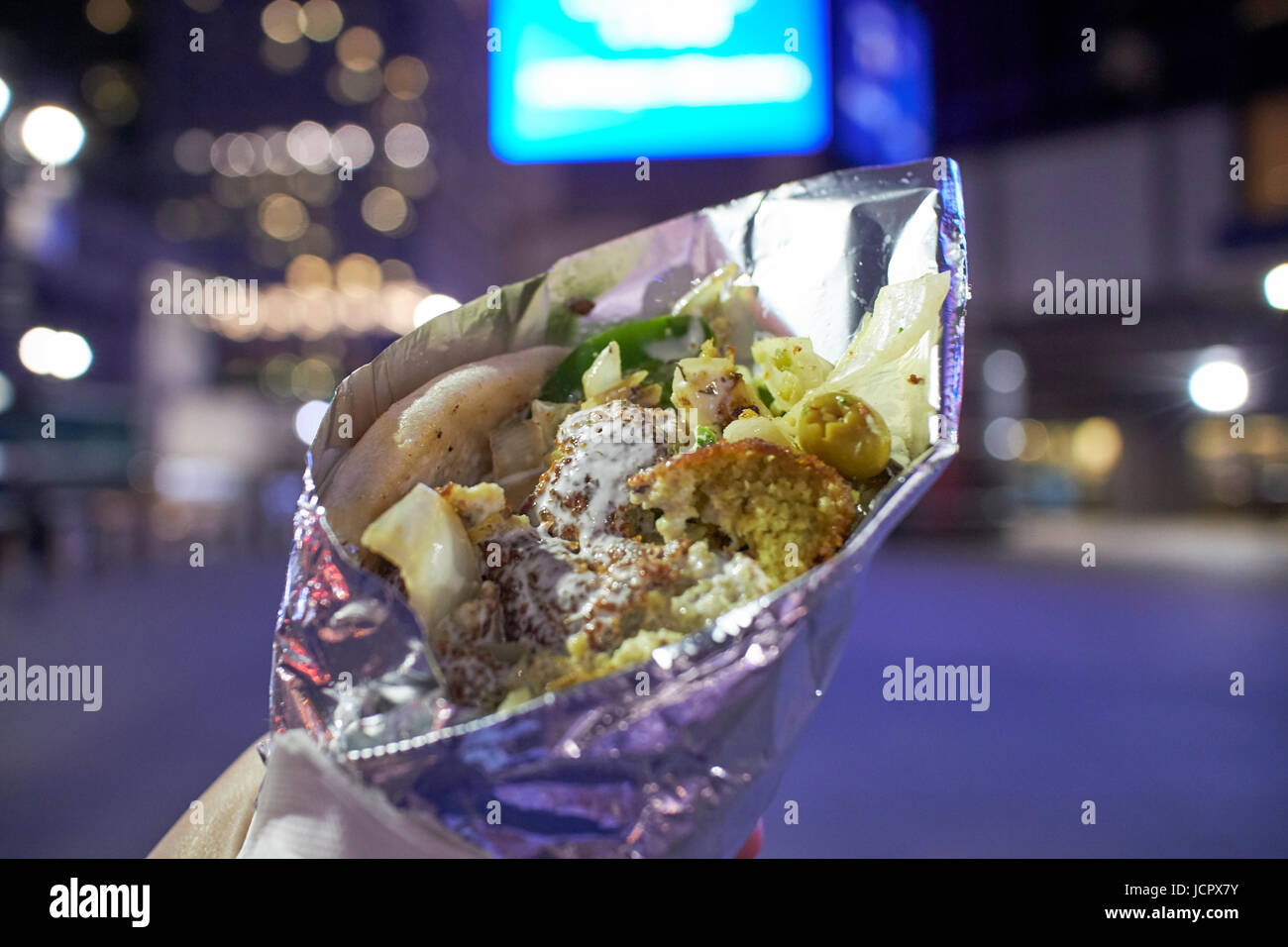 Sándwich de falafel street alimentos envueltos en papel de aluminio en la noche la ciudad de Nueva York EE.UU. Foto de stock