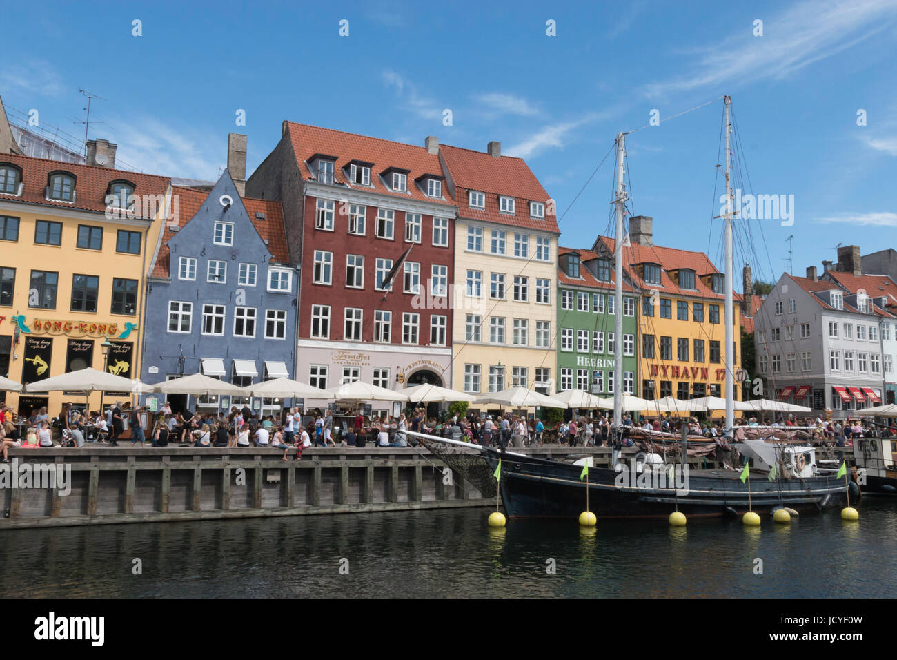 La multitud se reúne junto al muelle de Nyhavn, Copenhague en un brillante día de verano. un barco está amarrado en el canal. Foto de stock