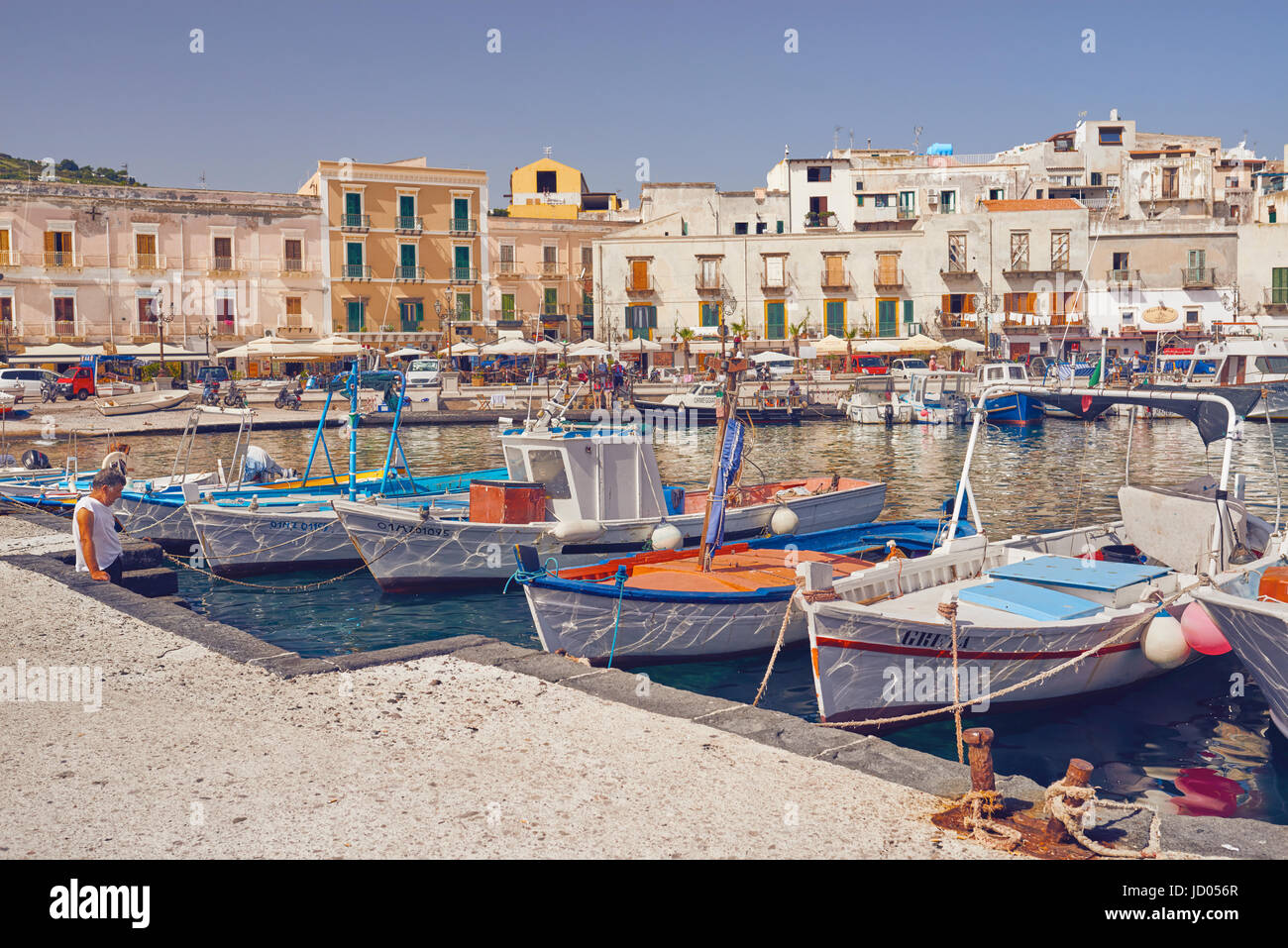 Las Islas Eolias, Lípari, Sicilia, Italia, Junio 8 / 2016. Puerto de Lipari, barcos de pesca y el pescador sentado en el muelle. Foto de stock