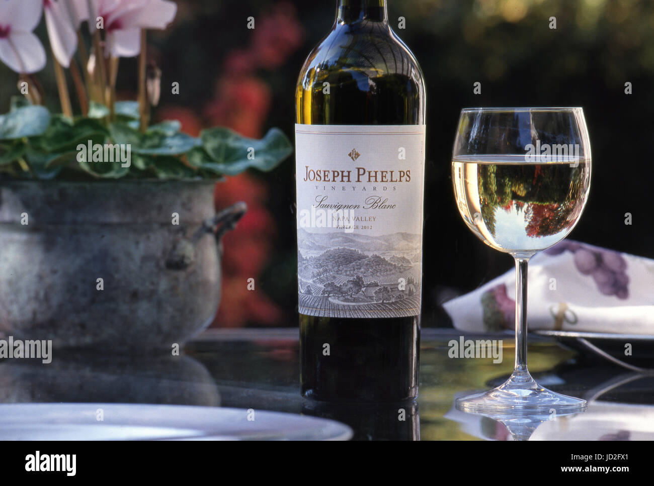 Joseph Phelps Sauvignon Blanc botella de vino blanco y copa, con reflejos florales en una elegante mesa de almuerzo al aire libre, Napa Valley, California. EE.UU Foto de stock