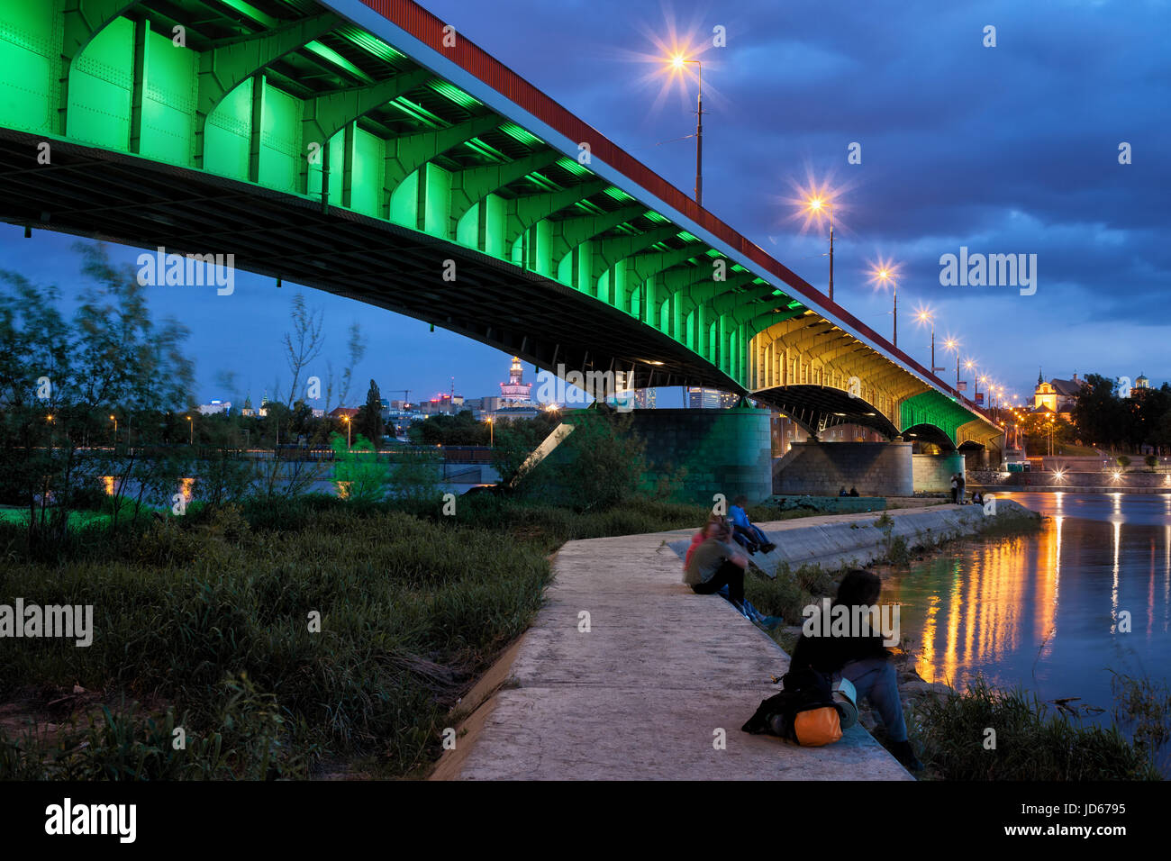Polonia, la ciudad de Varsovia, iluminado Puente Slasko-Dabrowski y un muelle en el río Vístula al atardecer Foto de stock
