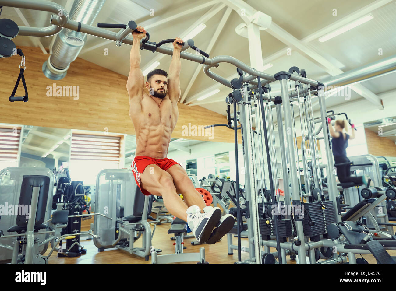 Un hombre haciendo ejercicios de abs en tirar hacia arriba en la barra de gimnasio Foto de stock