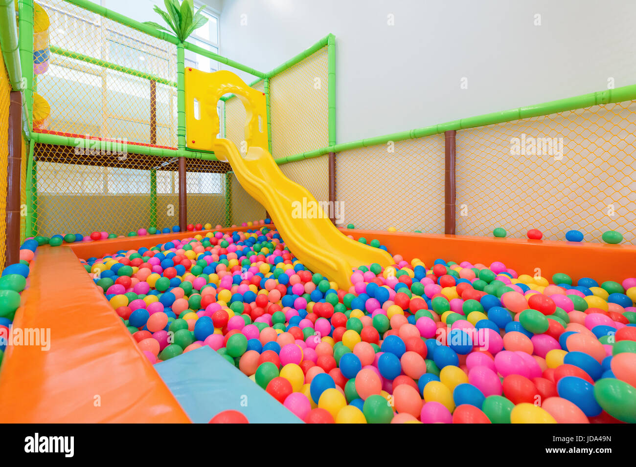 Parque infantil con Control deslizante de plástico amarillo y coloridas bolas de plástico en la piscina. Foto de stock